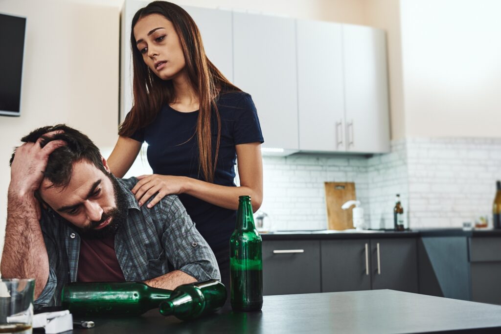 Alcoholic man and depressed wife in kitchen